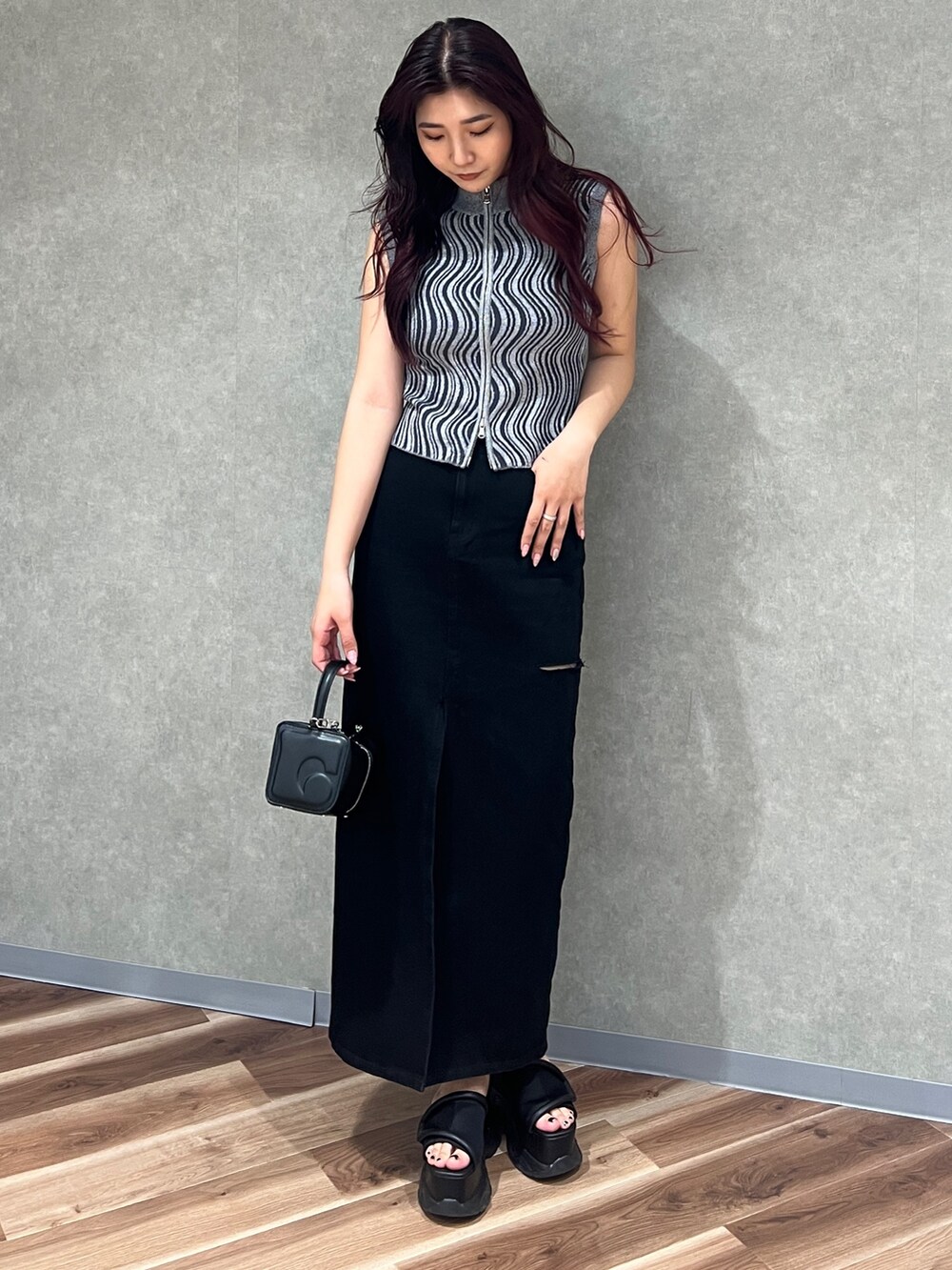 グレー系のタンクトップ、ブラック系のデニムスカート、ブラック系のハンドバッグを着用したレディースの夏コーディネートの3枚目の写真