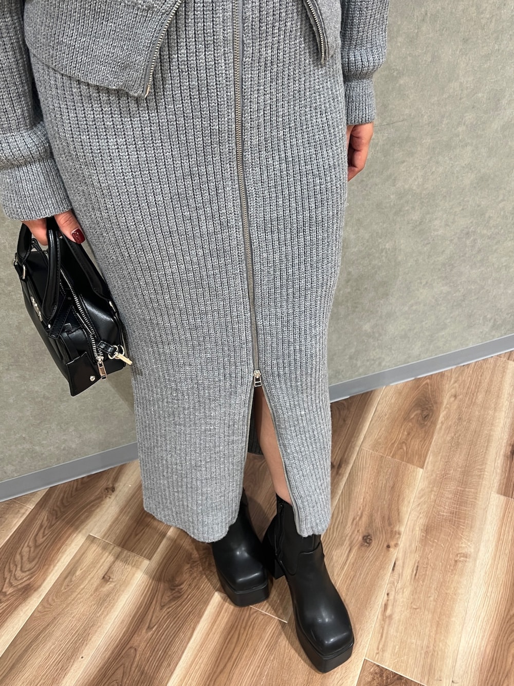 グレー系のスカート、グレー系のニット/セーター、ブラック系のブーツを着用したレディースの冬コーディネートの6枚目の写真