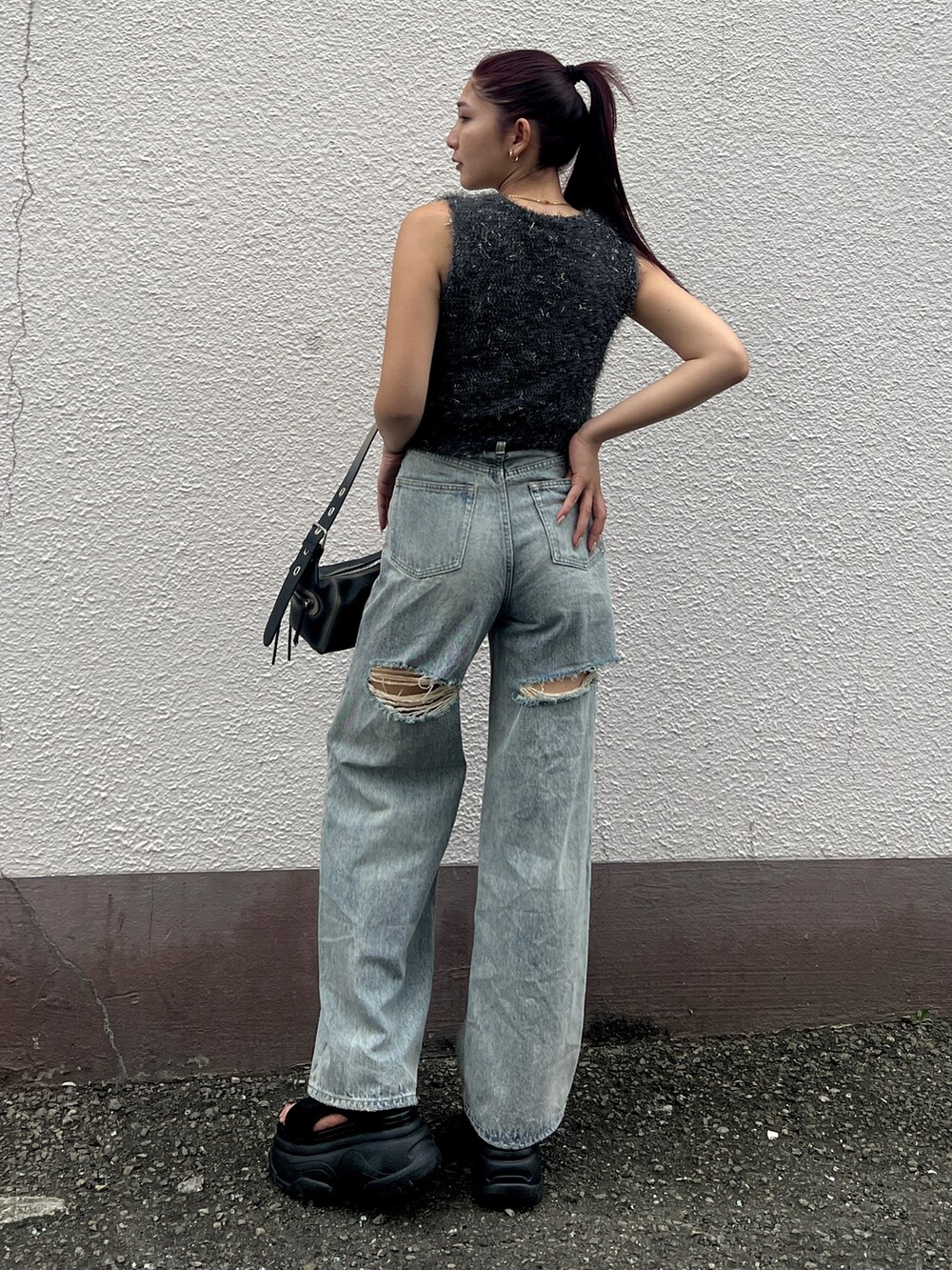 グレー系のタンクトップ、ブルー系のデニムパンツ、ブラック系のハンドバッグを着用したレディースの夏コーディネートの2枚目の写真