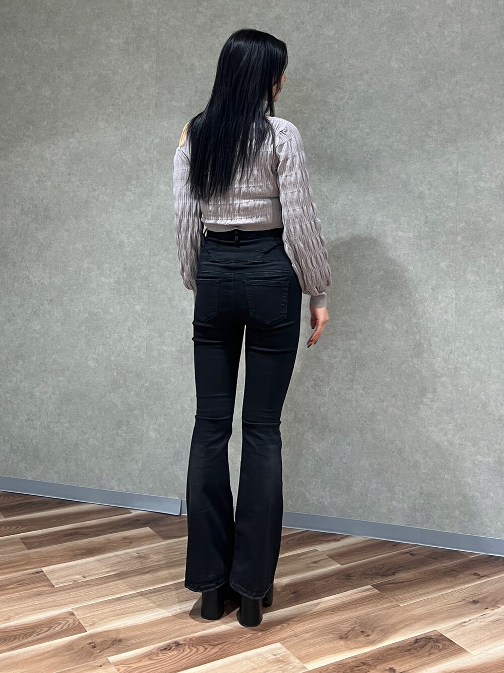 グレー系のニット/セーター、ブラック系のブーツ、ブラック系のデニムパンツを着用したレディースの春コーディネートの3枚目の写真