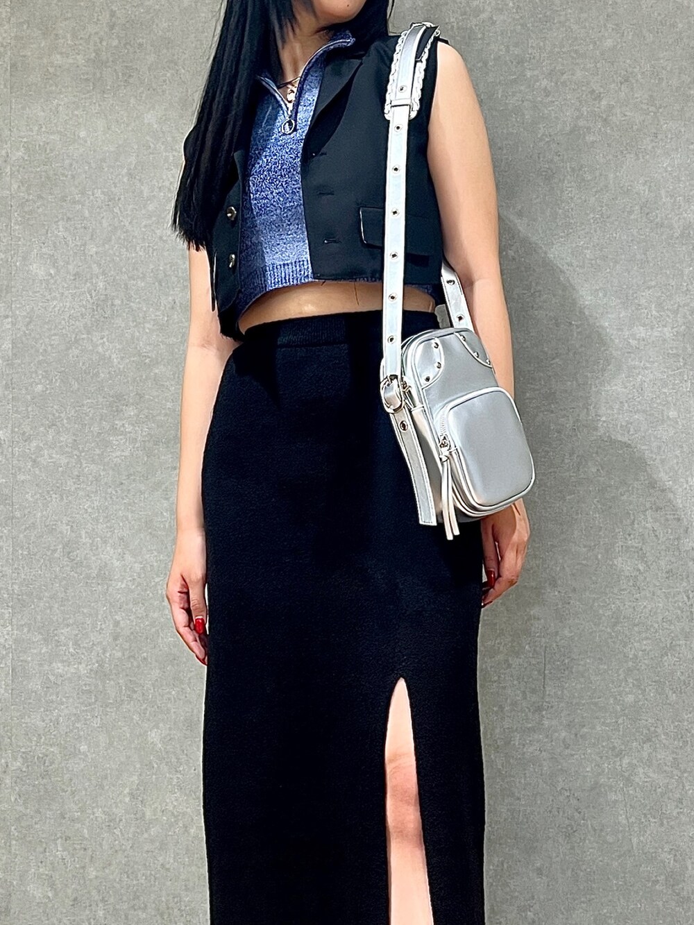 ブラック系のスカート、シルバー系のショルダーバッグ、ブラック系のブーツを着用したレディースの夏コーディネートの2枚目の写真