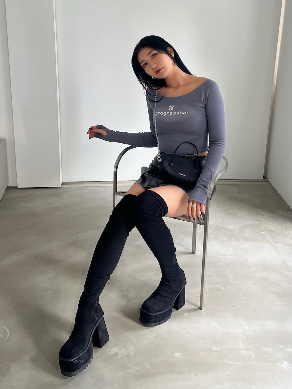 グレー系のTシャツ/カットソー、ブラック系のスカート、ブラック系のブーツを着用したレディースの秋コーディネートの3枚目の写真