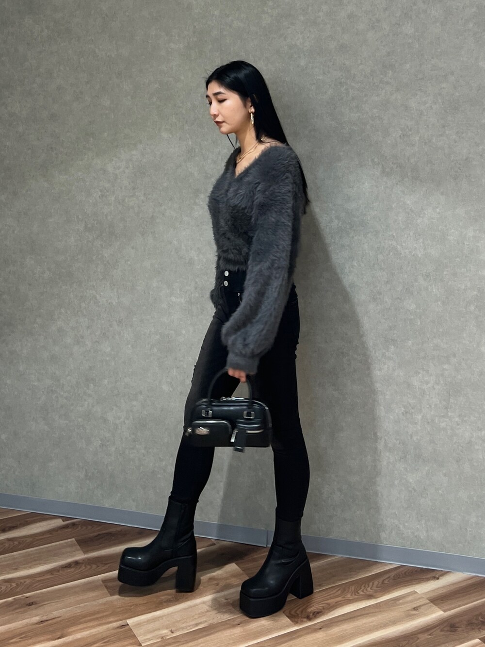 グレー系のニット/セーター、ブラック系のデニムパンツ、ブラック系のブーツを着用したレディースの秋コーディネートの3枚目の写真