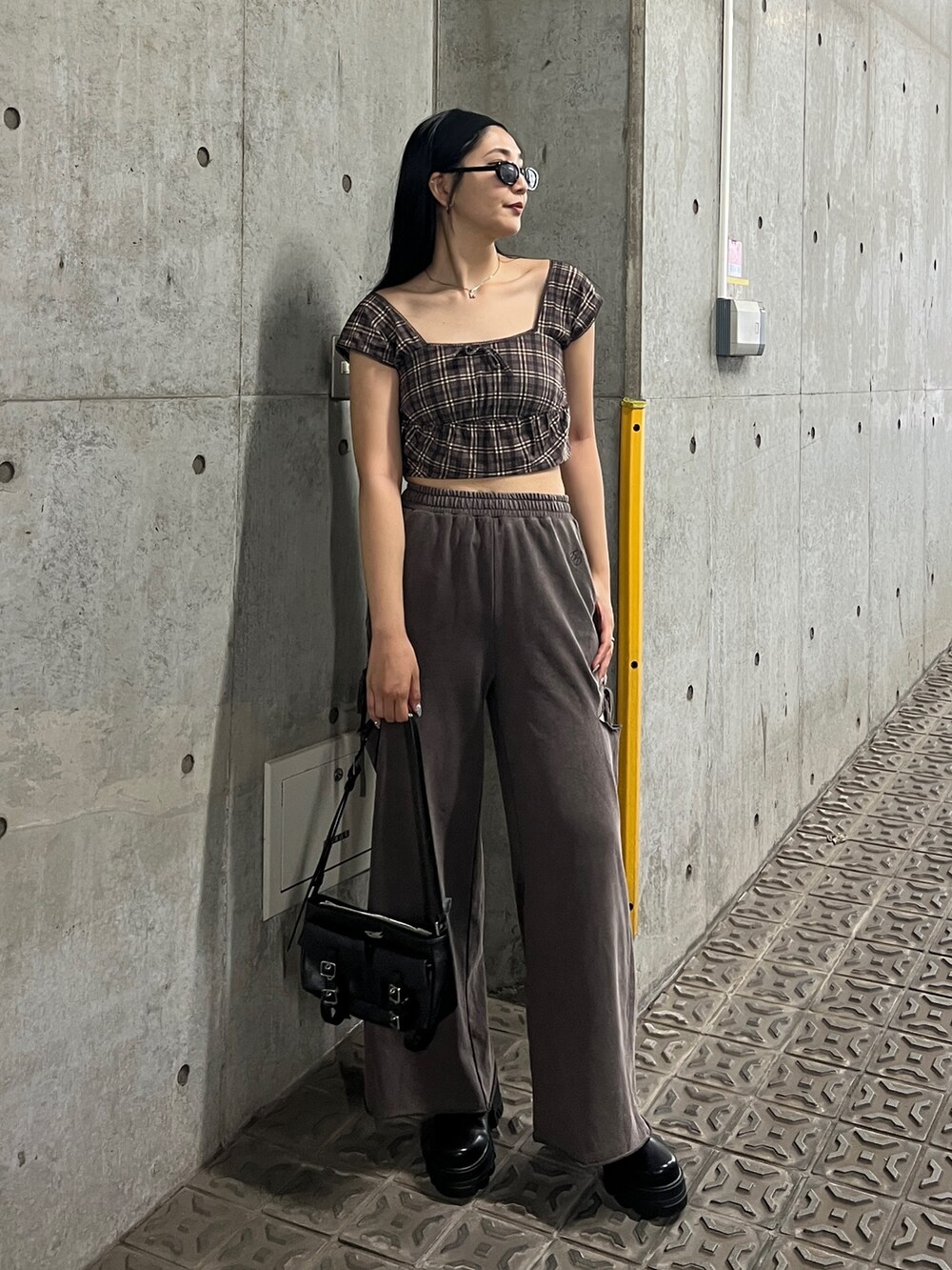 ブラウン系のタンクトップ、ブラウン系のスウェットパンツ、ブラック系のブーツを着用したレディースの夏コーディネートの3枚目の写真