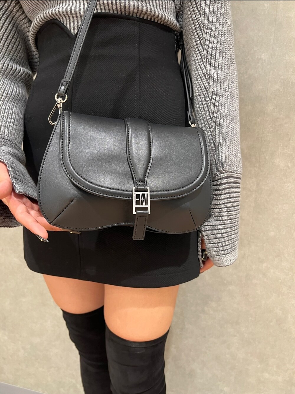 グレー系のニット/セーター、ブラック系のスカート、ブラック系のブーツを着用したレディースの秋コーディネートの5枚目の写真