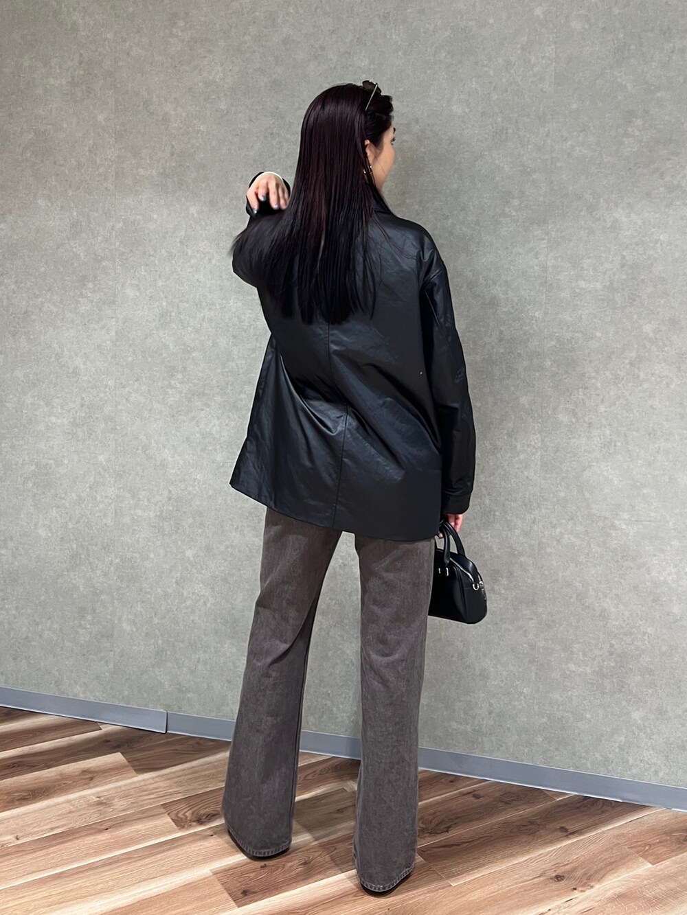 ブラック系のナイロンジャケット、ブラウン系のデニムパンツ、ブラック系のパンプスを着用したレディースの春コーディネートの3枚目の写真