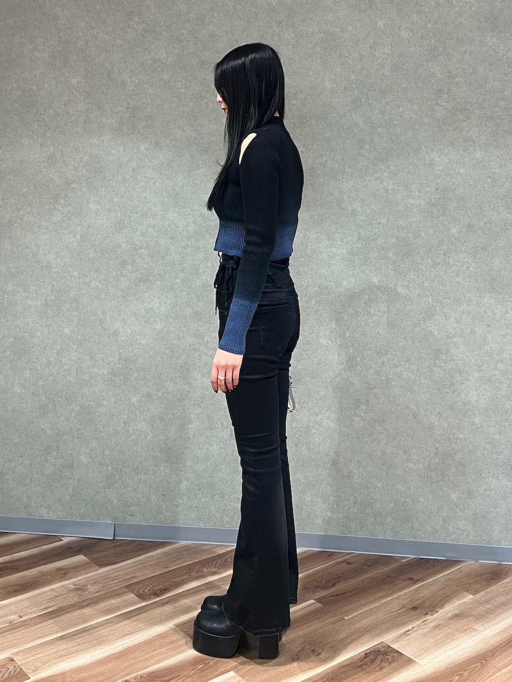 ブラック系のニット/セーター、ブラック系のデニムパンツ、ブラック系のブーツを着用したレディースの春コーディネートの2枚目の写真