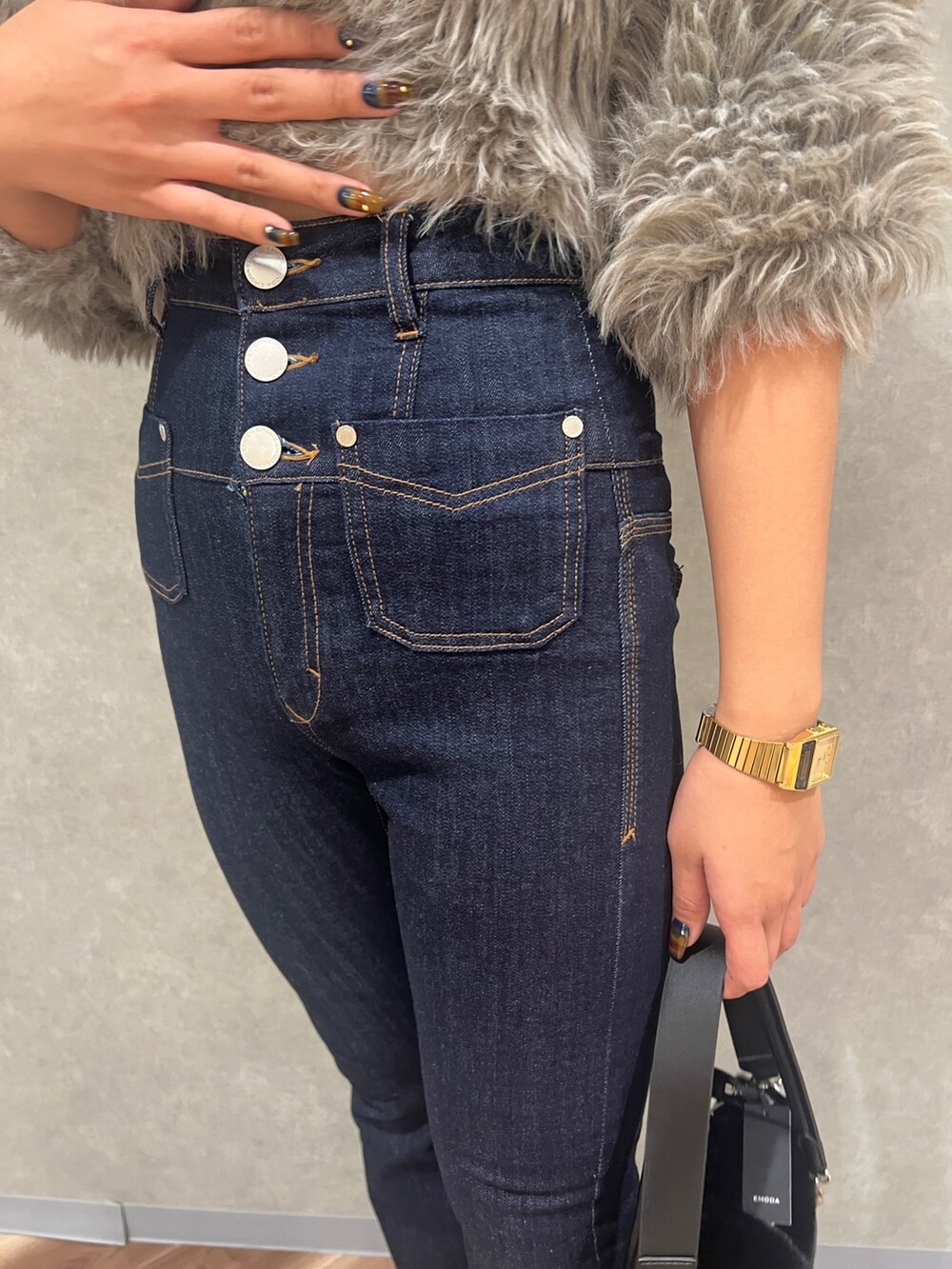 グレー系のニット/セーター、ブルー系のデニムパンツ、ブラック系のハンドバッグを着用したレディースの秋コーディネートの6枚目の写真