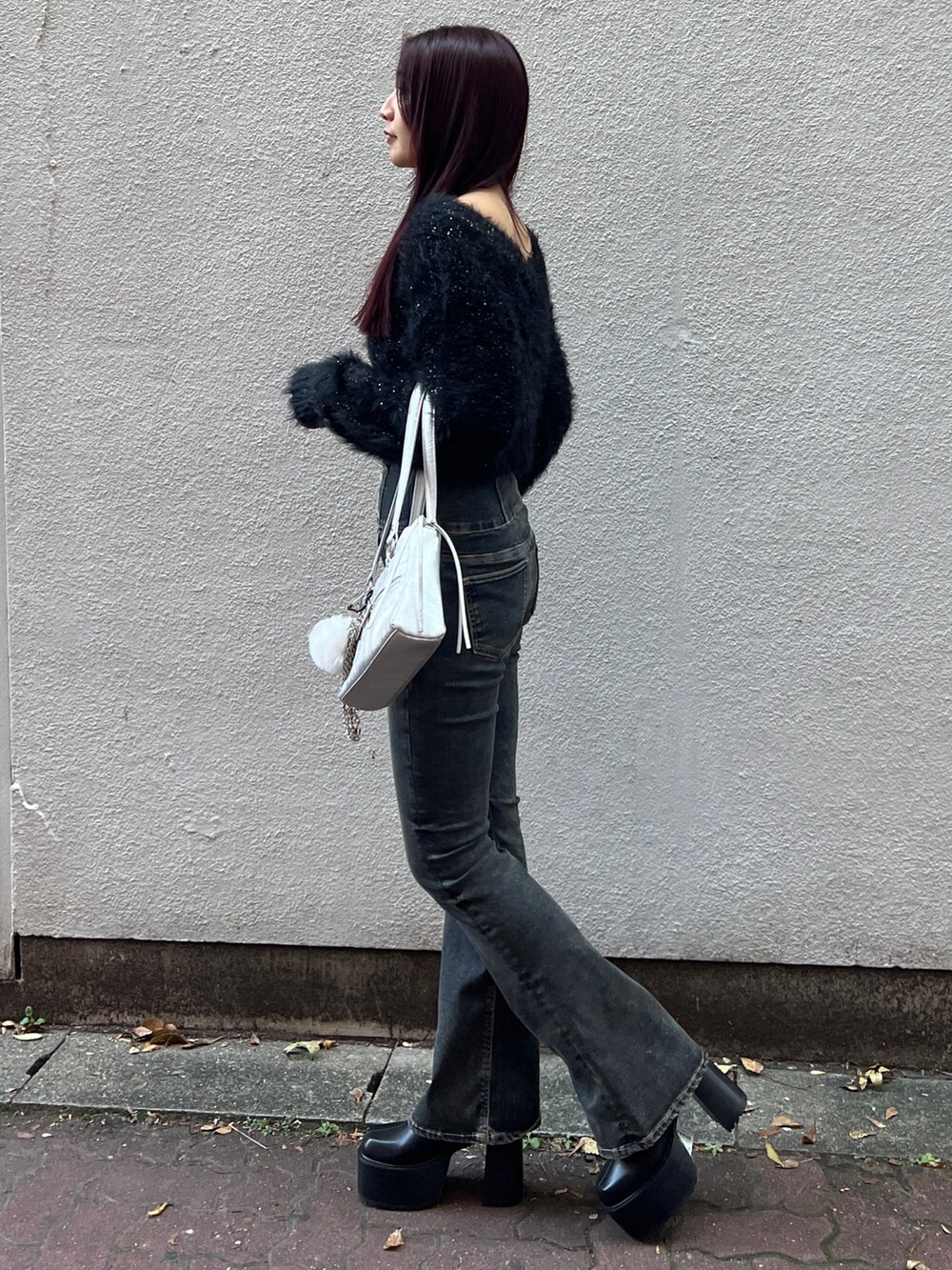 ブラック系のニット/セーター、ブルー系のデニムパンツ、ブラック系のブーツを着用したレディースの秋コーディネートの2枚目の写真