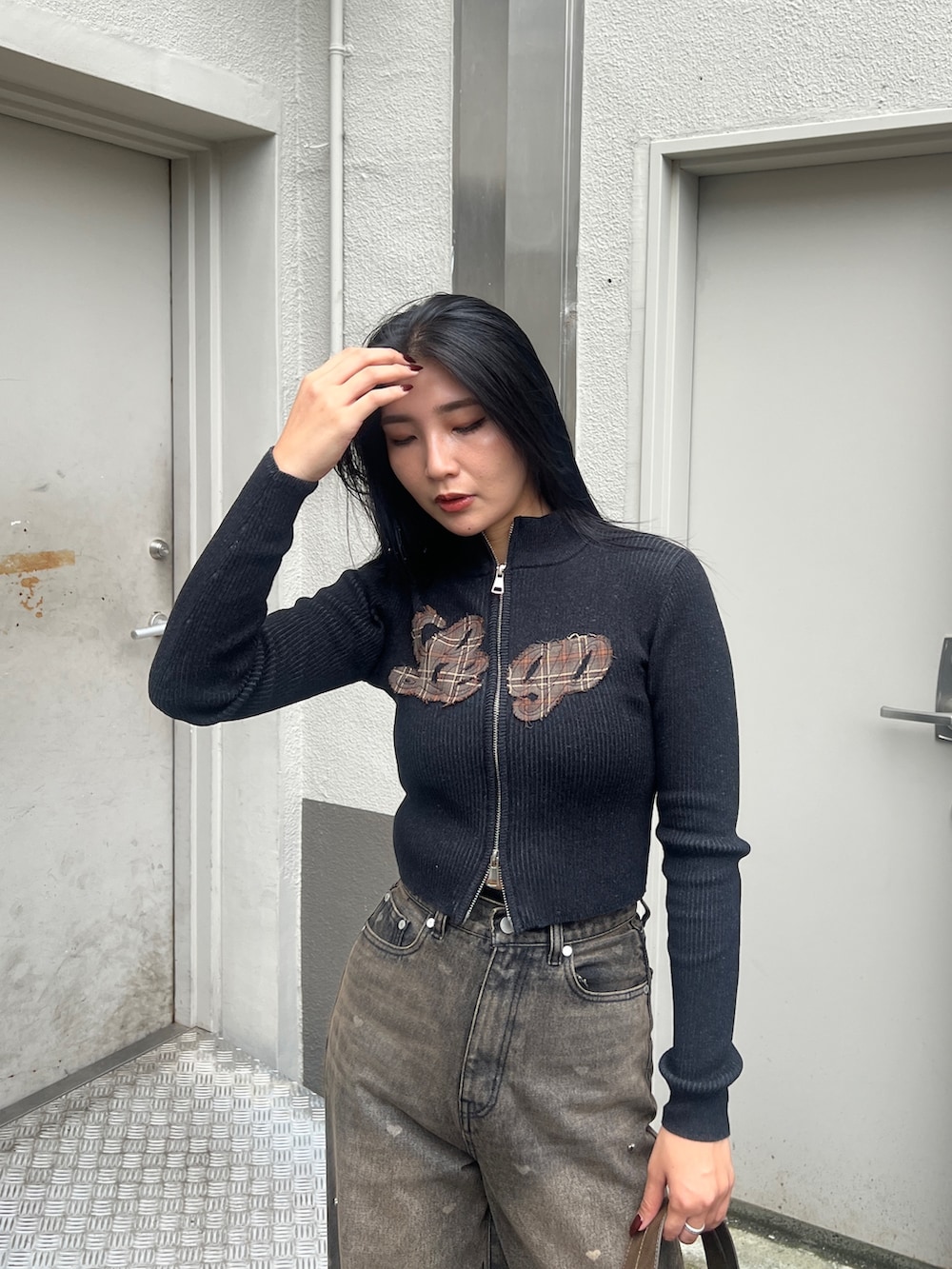 ブラック系のブルゾン、ブラック系のニット/セーター、ブラウン系のデニムパンツを着用したレディースの秋コーディネートの4枚目の写真