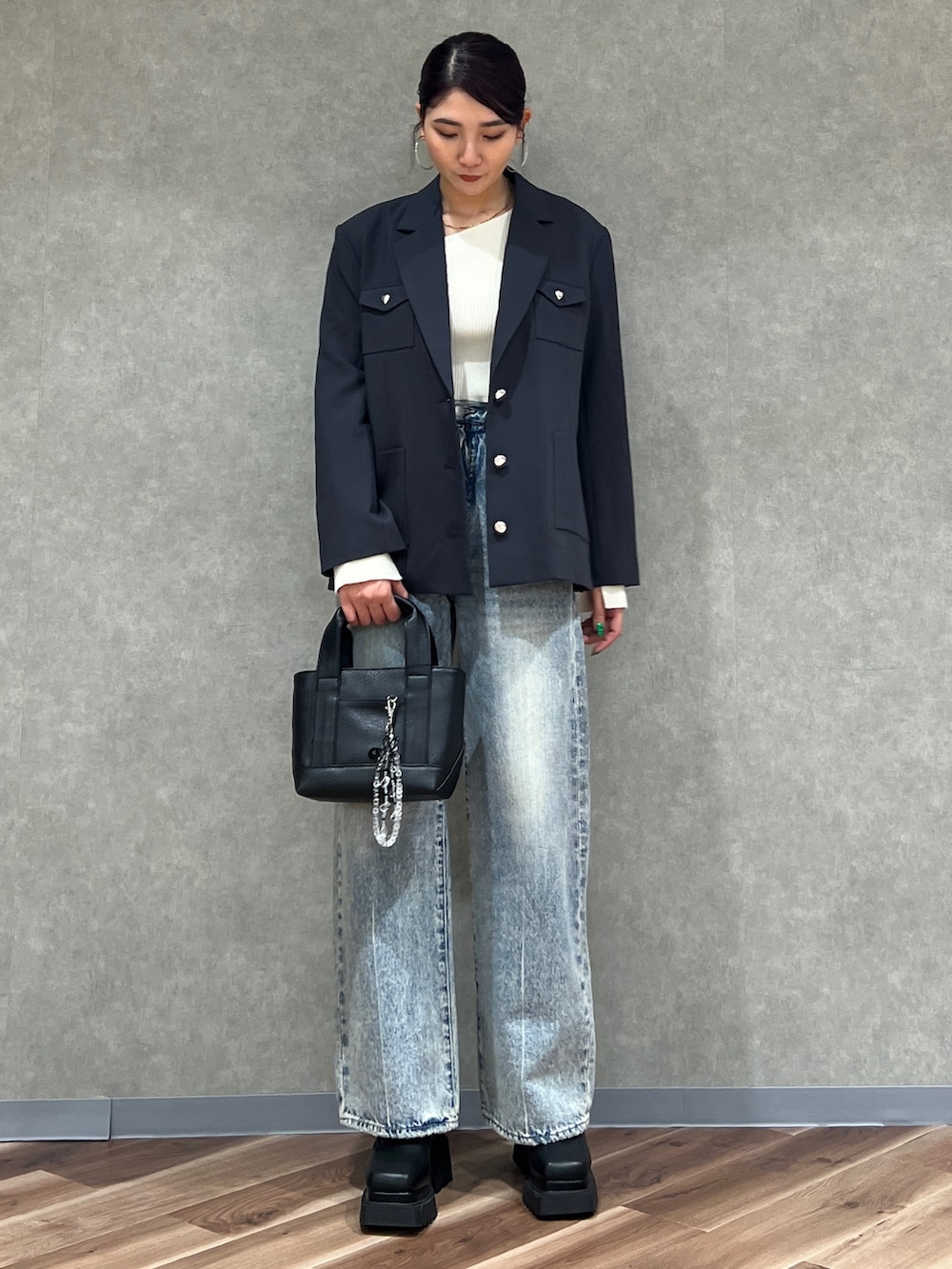 グレー系のテーラードジャケット、ブルー系のデニムパンツ、ブラック系のブーツを着用したレディースの冬コーディネートの2枚目の写真