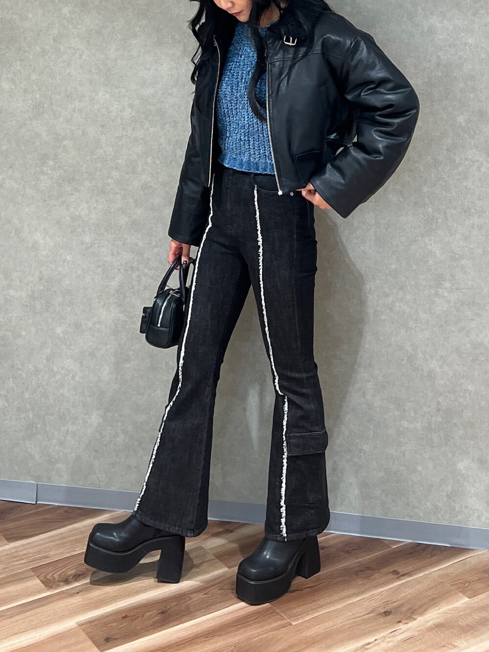 ブラック系のブルゾン、ブルー系のニット/セーター、ブラック系のデニムパンツを着用したレディースの秋コーディネートの2枚目の写真