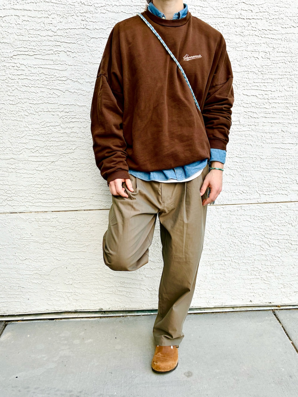 ブラウン系のスウェット、ベージュ系のスラックス、ブルー系のシャツ/ブラウスを着用したメンズの冬コーディネートの4枚目の写真