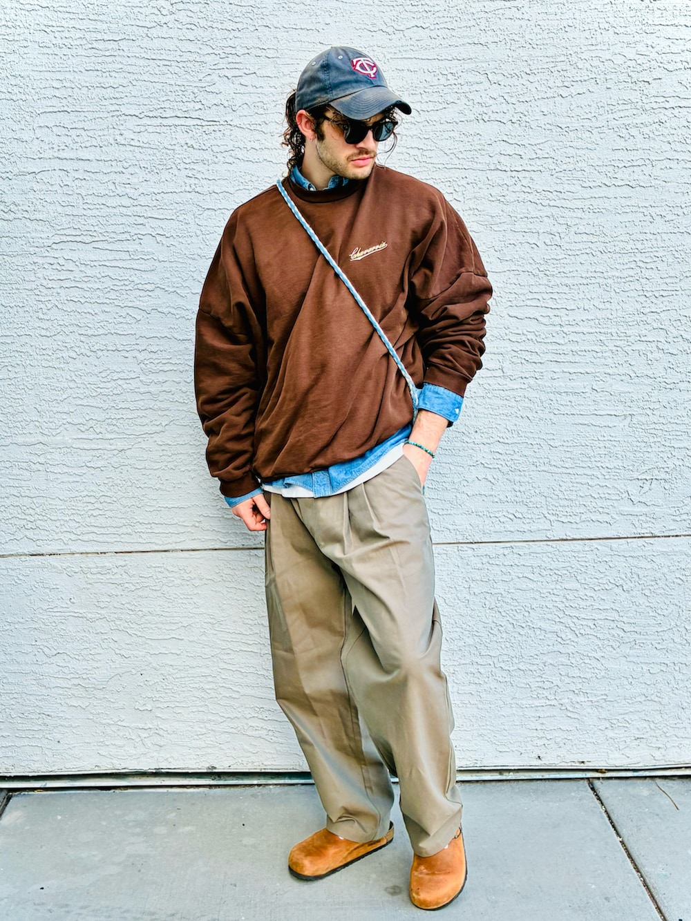 ブラウン系のスウェット、ベージュ系のスラックス、ブルー系のシャツ/ブラウスを着用したメンズの冬コーディネートの2枚目の写真