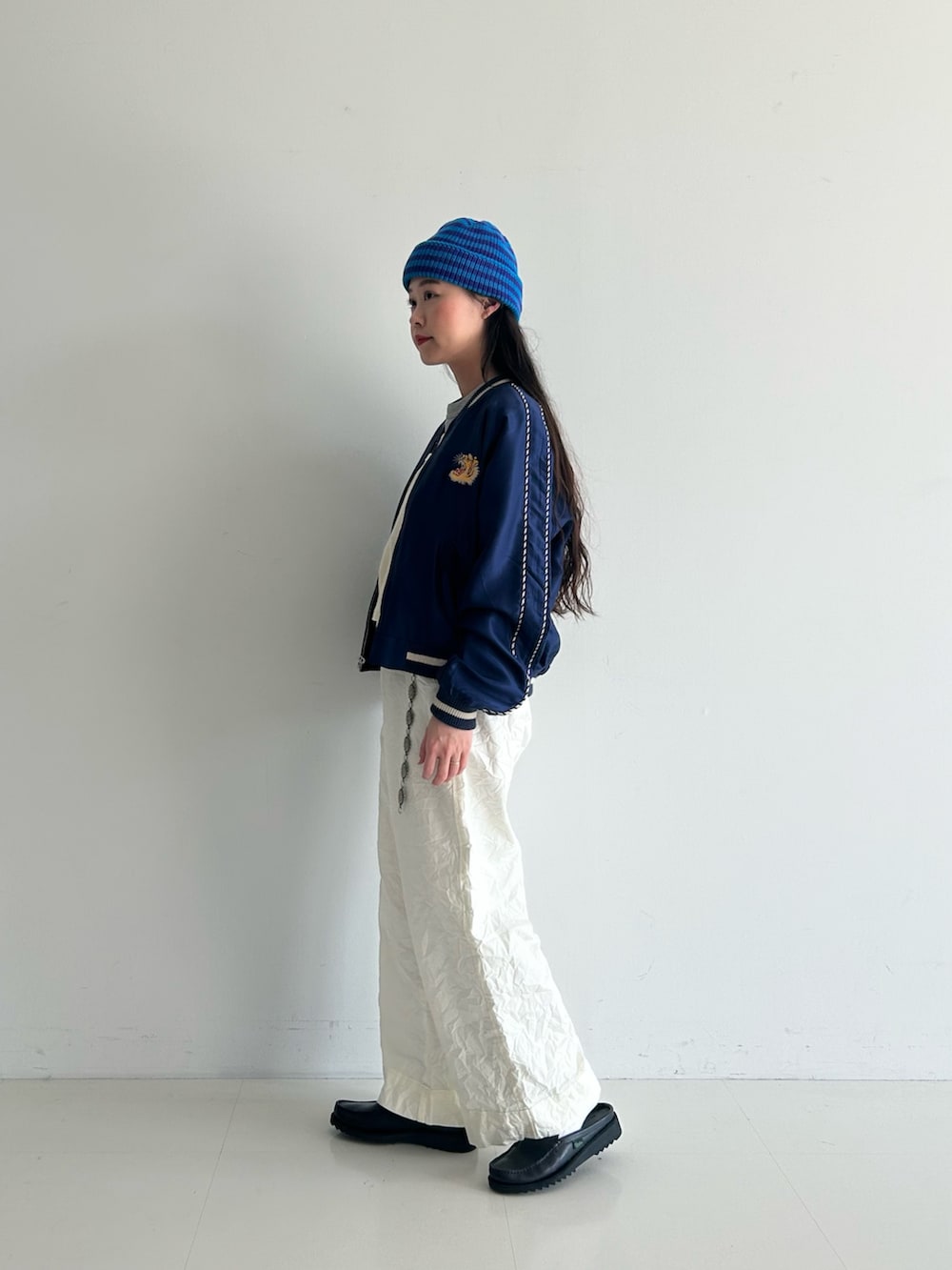 ホワイト系のスラックス、ブルー系のスカジャン、ホワイト系のタンクトップを着用したレディースの春コーディネートの2枚目の写真