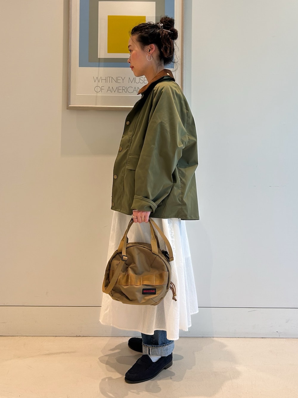 グリーン系のブルゾン、ホワイト系のTシャツ/カットソー、ブルー系のデニムパンツを着用したレディースの冬コーディネートの2枚目の写真