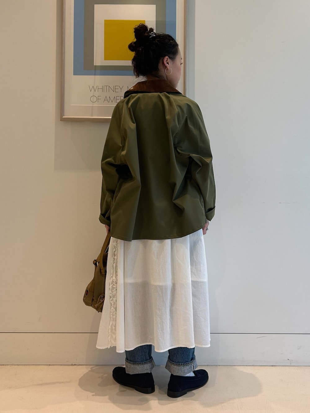 グリーン系のブルゾン、ホワイト系のTシャツ/カットソー、ブルー系のデニムパンツを着用したレディースの冬コーディネートの3枚目の写真