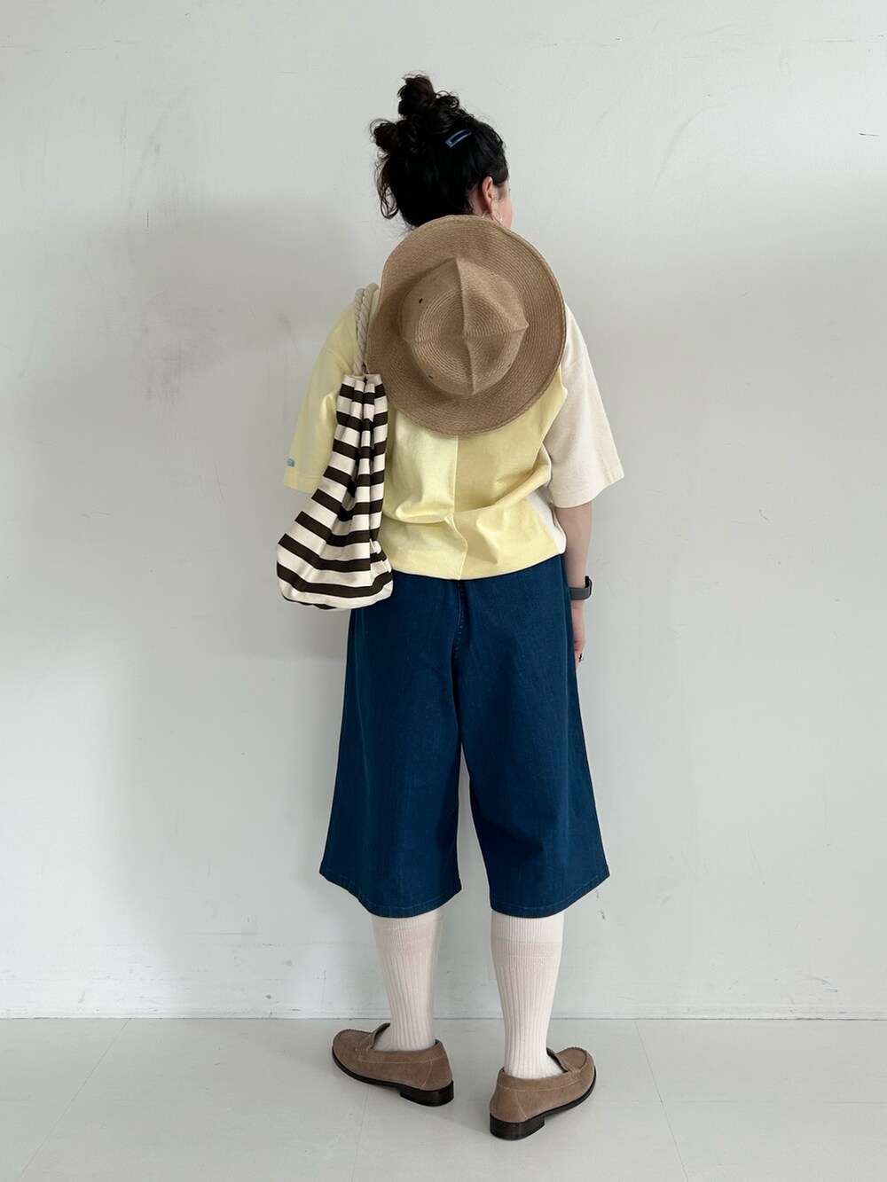 ブラウン系のバックパック/リュック、ブルー系のデニムパンツ、ベージュ系のローファーを着用したレディースの春コーディネートの3枚目の写真