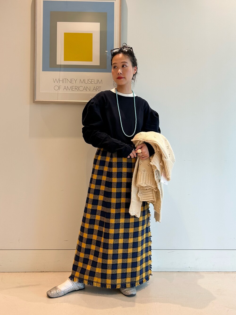 イエロー系のスカート、ホワイト系のカーディガン/ボレロ、ブラック系のメガネを着用したレディースの秋コーディネートの6枚目の写真