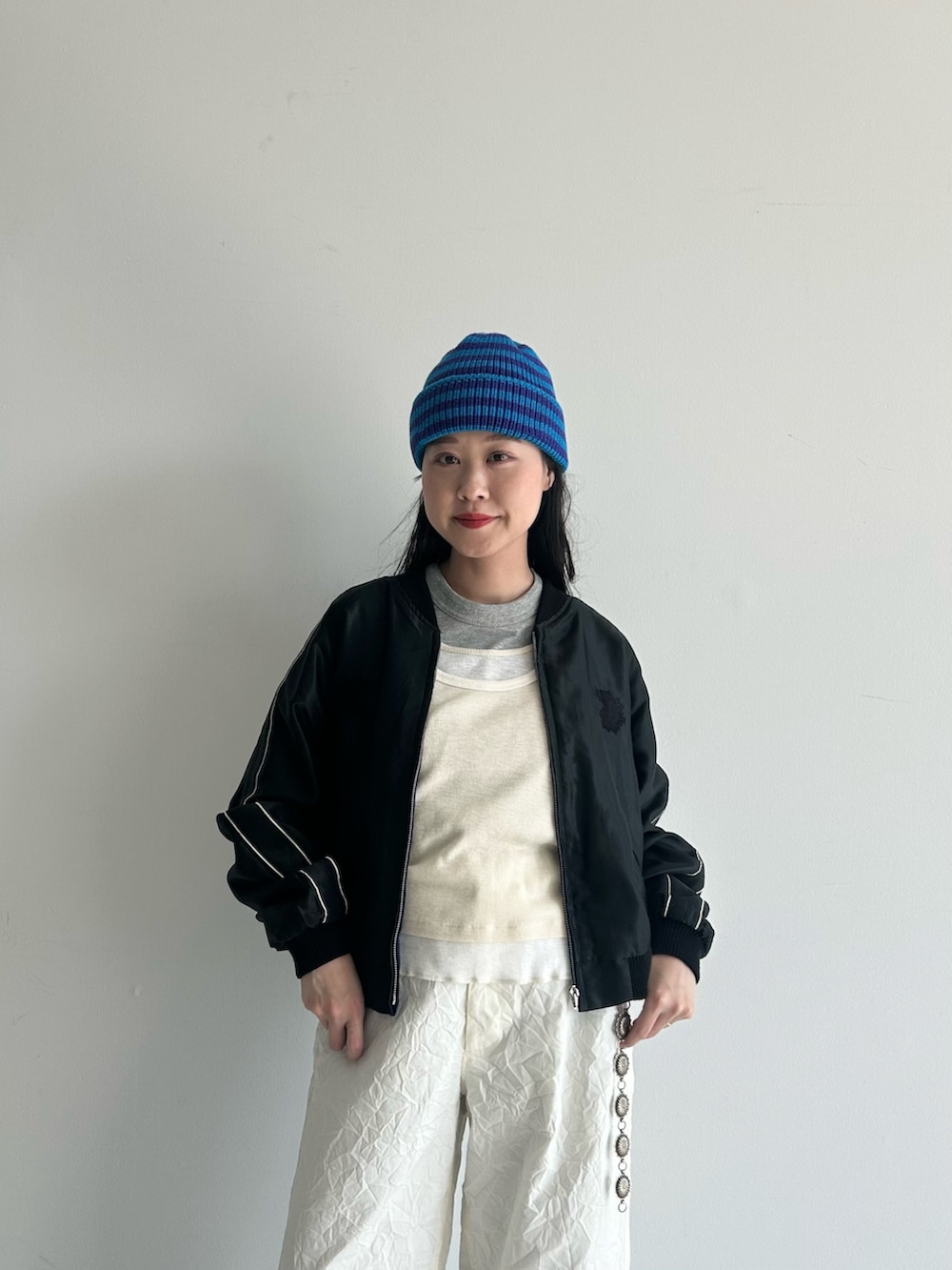 ホワイト系のスラックス、ブルー系のスカジャン、ホワイト系のタンクトップを着用したレディースの春コーディネートの7枚目の写真