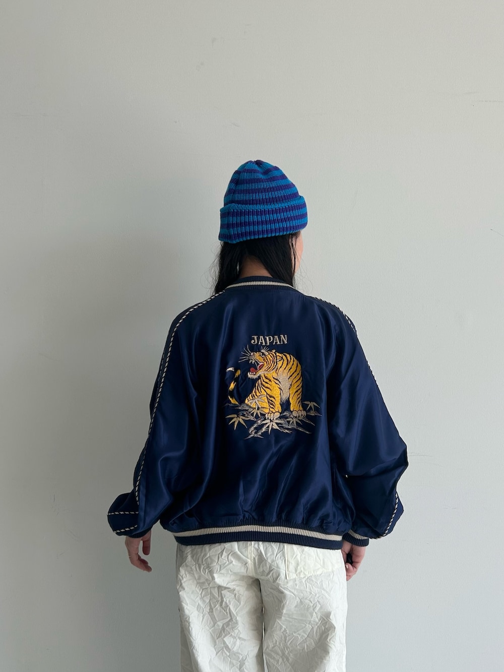 ホワイト系のスラックス、ブルー系のスカジャン、ホワイト系のタンクトップを着用したレディースの春コーディネートの6枚目の写真