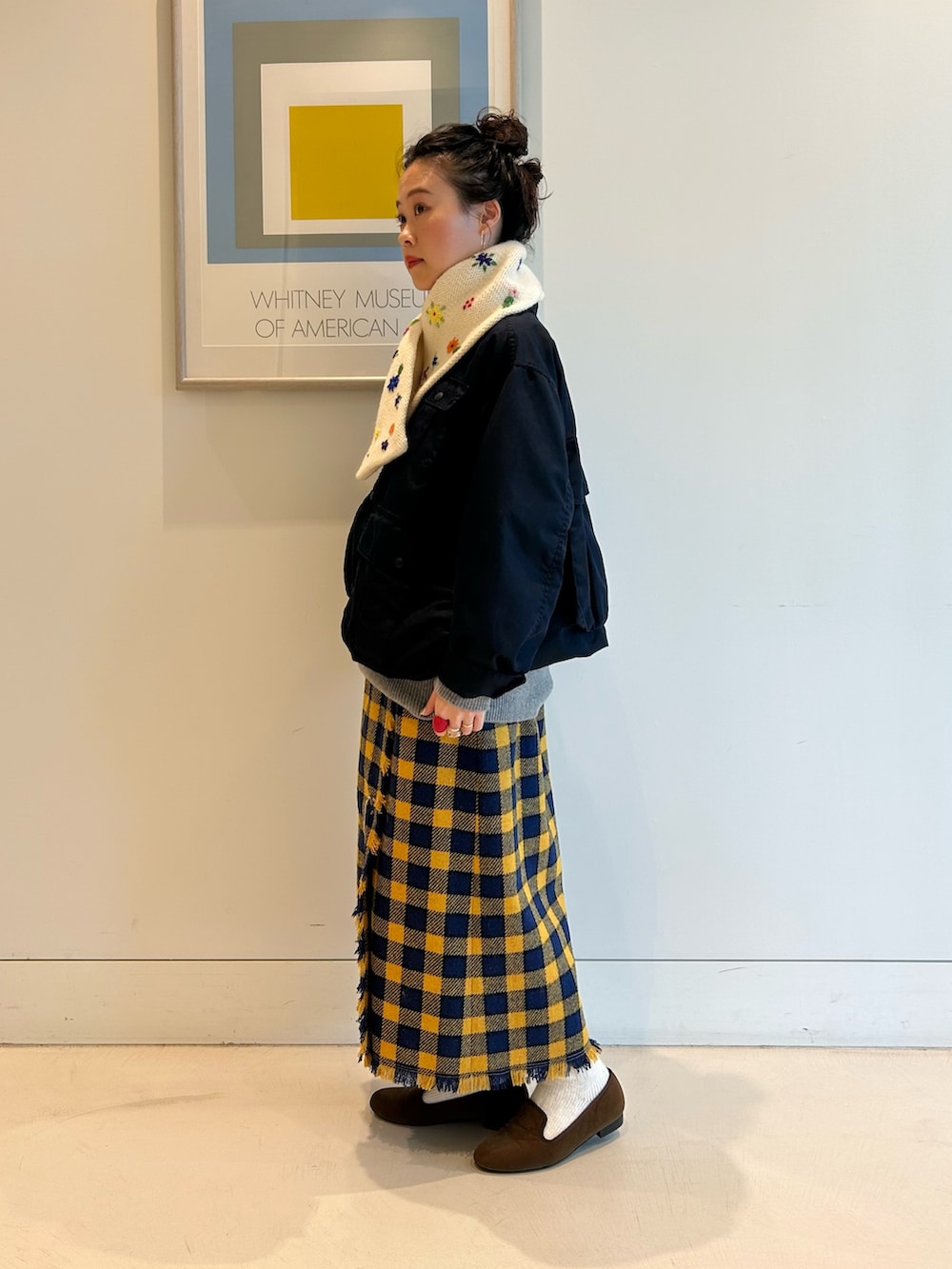 ブルー系のミリタリージャケット、イエロー系のスカート、ブラウン系のドレスシューズを着用したレディースの夏コーディネートの2枚目の写真