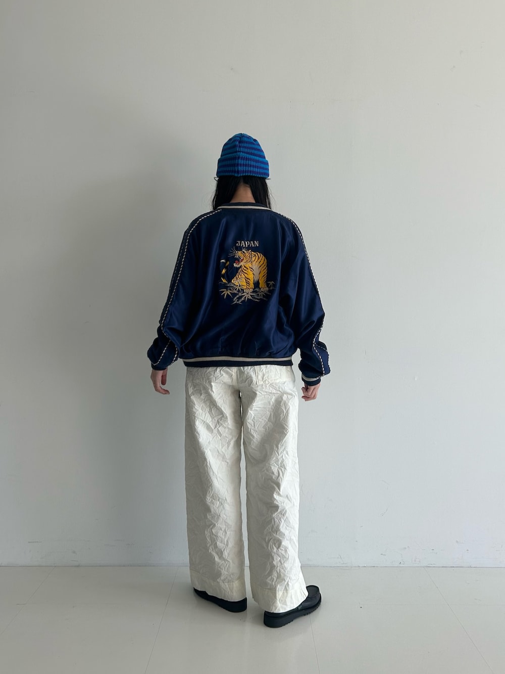 ホワイト系のスラックス、ブルー系のスカジャン、ホワイト系のタンクトップを着用したレディースの春コーディネートの3枚目の写真