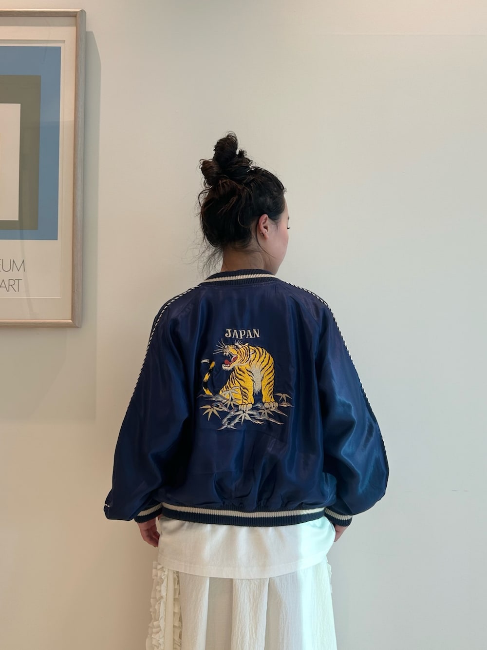 ブルー系のスカジャン、ホワイト系のスカート、ブラック系のローファーを着用したレディースの春コーディネートの4枚目の写真