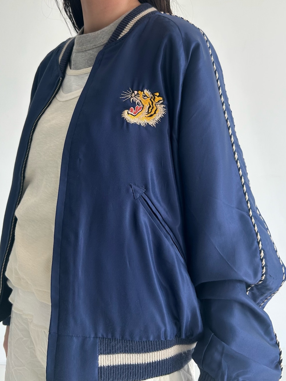 ホワイト系のスラックス、ブルー系のスカジャン、ホワイト系のタンクトップを着用したレディースの春コーディネートの5枚目の写真