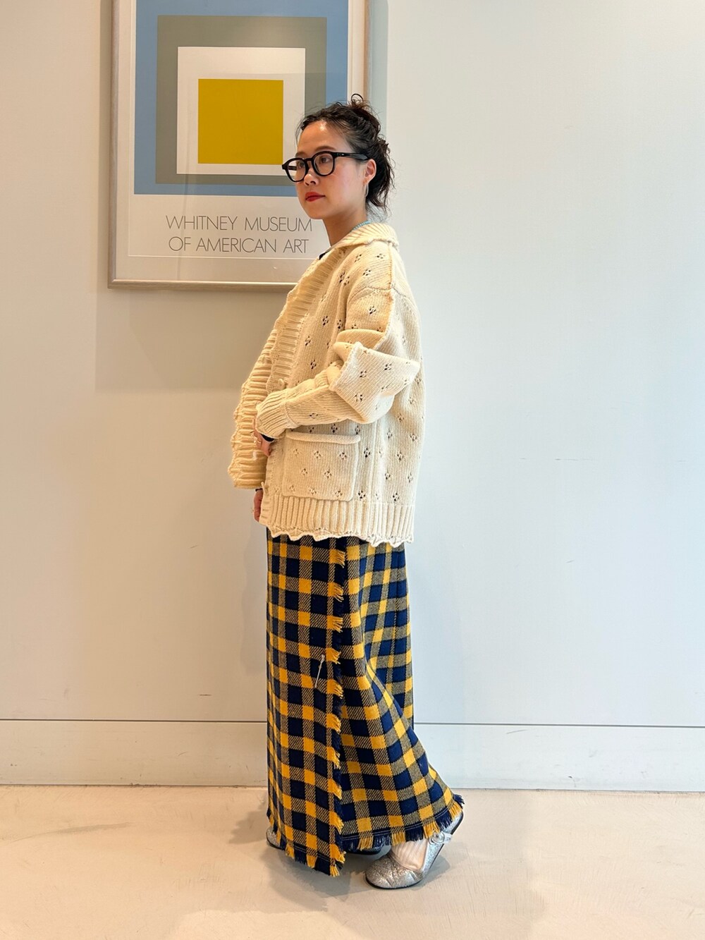 イエロー系のスカート、ホワイト系のカーディガン/ボレロ、ブラック系のメガネを着用したレディースの秋コーディネートの3枚目の写真