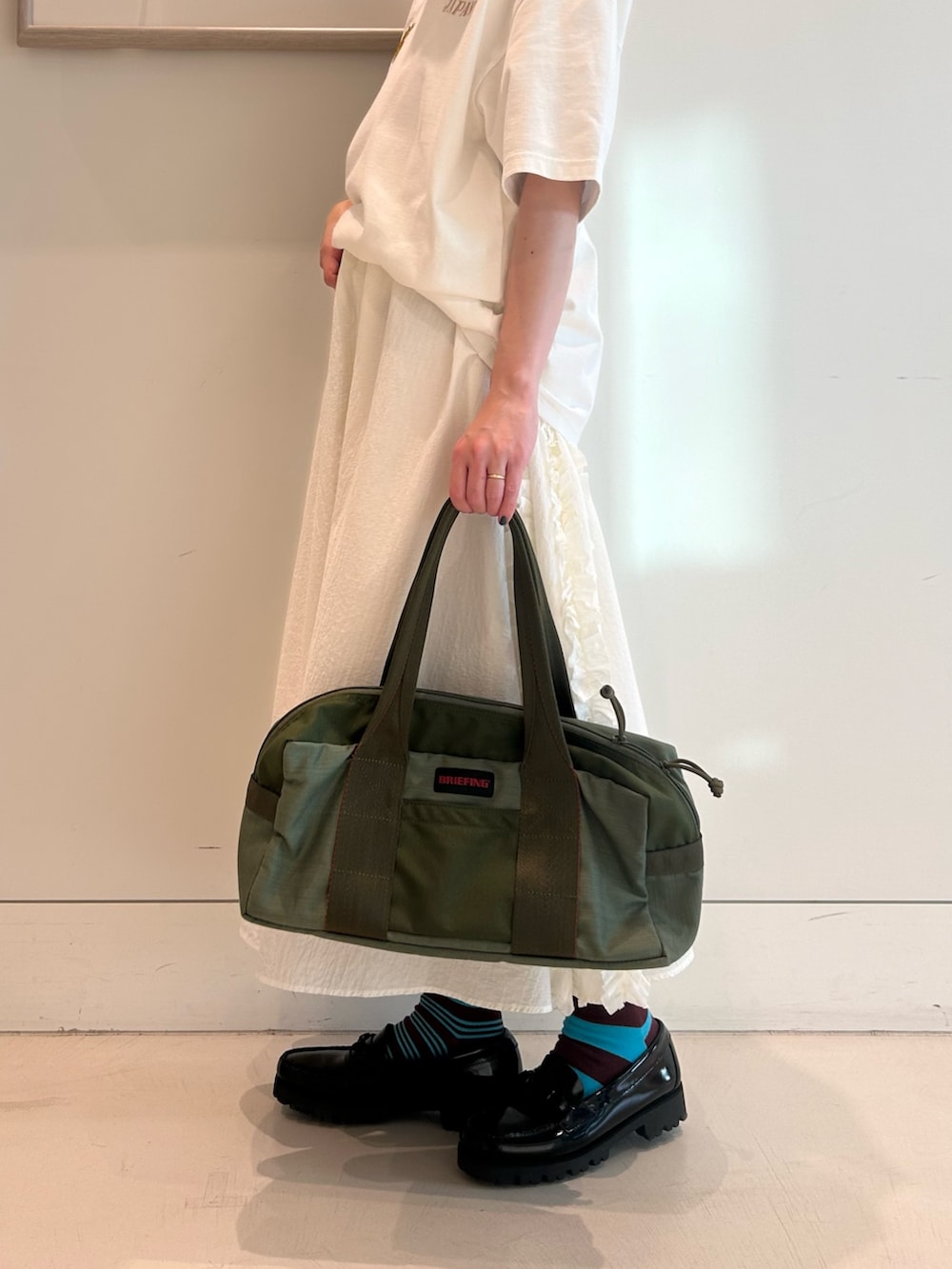 ブルー系のスカジャン、ホワイト系のスカート、ブラック系のローファーを着用したレディースの春コーディネートの8枚目の写真