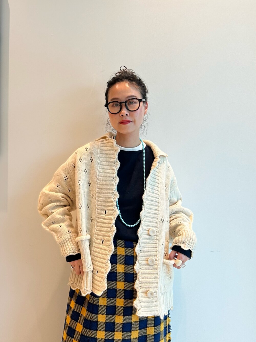 イエロー系のスカート、ホワイト系のカーディガン/ボレロ、ブラック系のメガネを着用したレディースの秋コーディネートの4枚目の写真