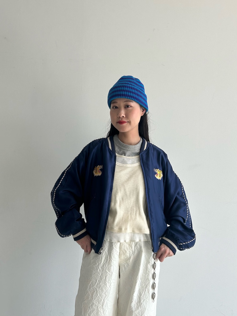 ホワイト系のスラックス、ブルー系のスカジャン、ホワイト系のタンクトップを着用したレディースの春コーディネートの4枚目の写真