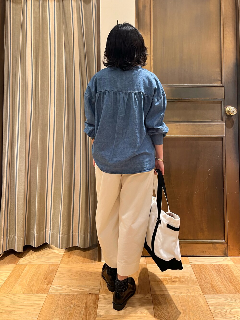 ブルー系のシャツ/ブラウス、ホワイト系のその他パンツ、ブラック系のハンドバッグを着用したレディースの春コーディネートの2枚目の写真