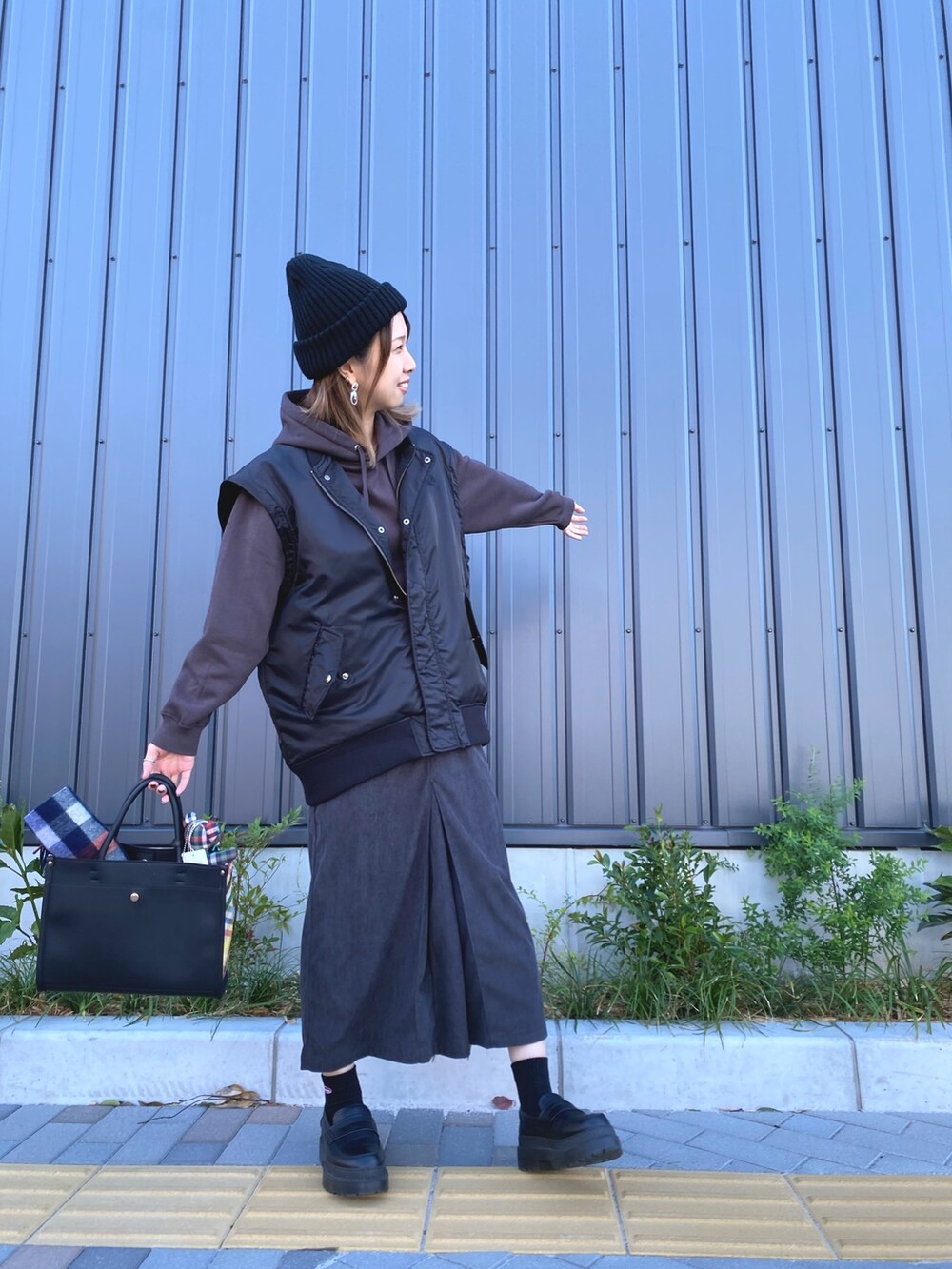 ブラック系のトートバッグ、ブラウン系のパーカー、ブラック系のブルゾンを着用したレディースの秋コーディネートの4枚目の写真
