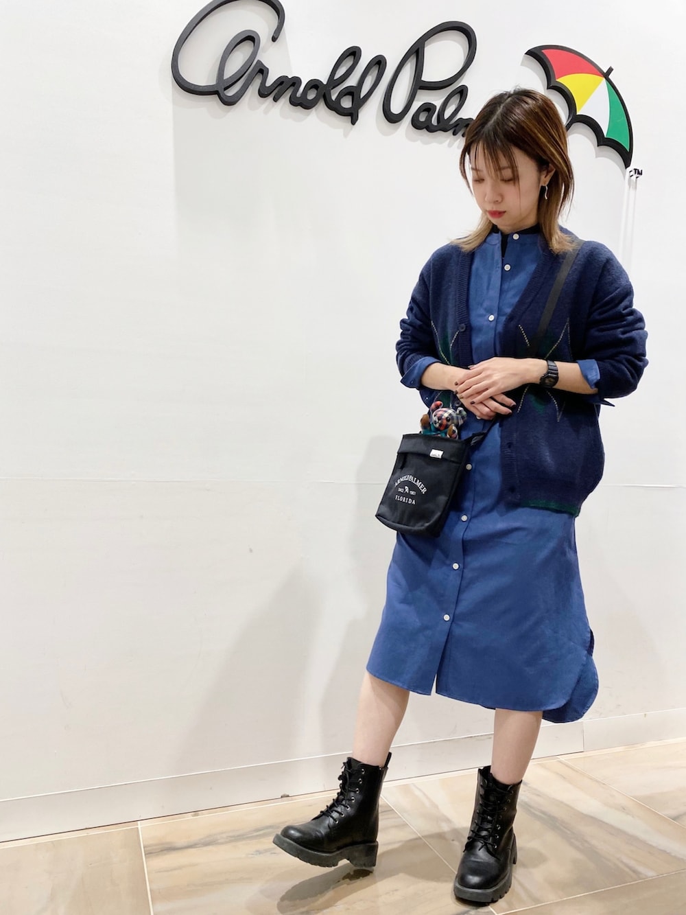 ブルー系のシャツワンピース、ブルー系のダウンベスト、ブラック系のショルダーバッグを着用したレディースの秋コーディネートの2枚目の写真