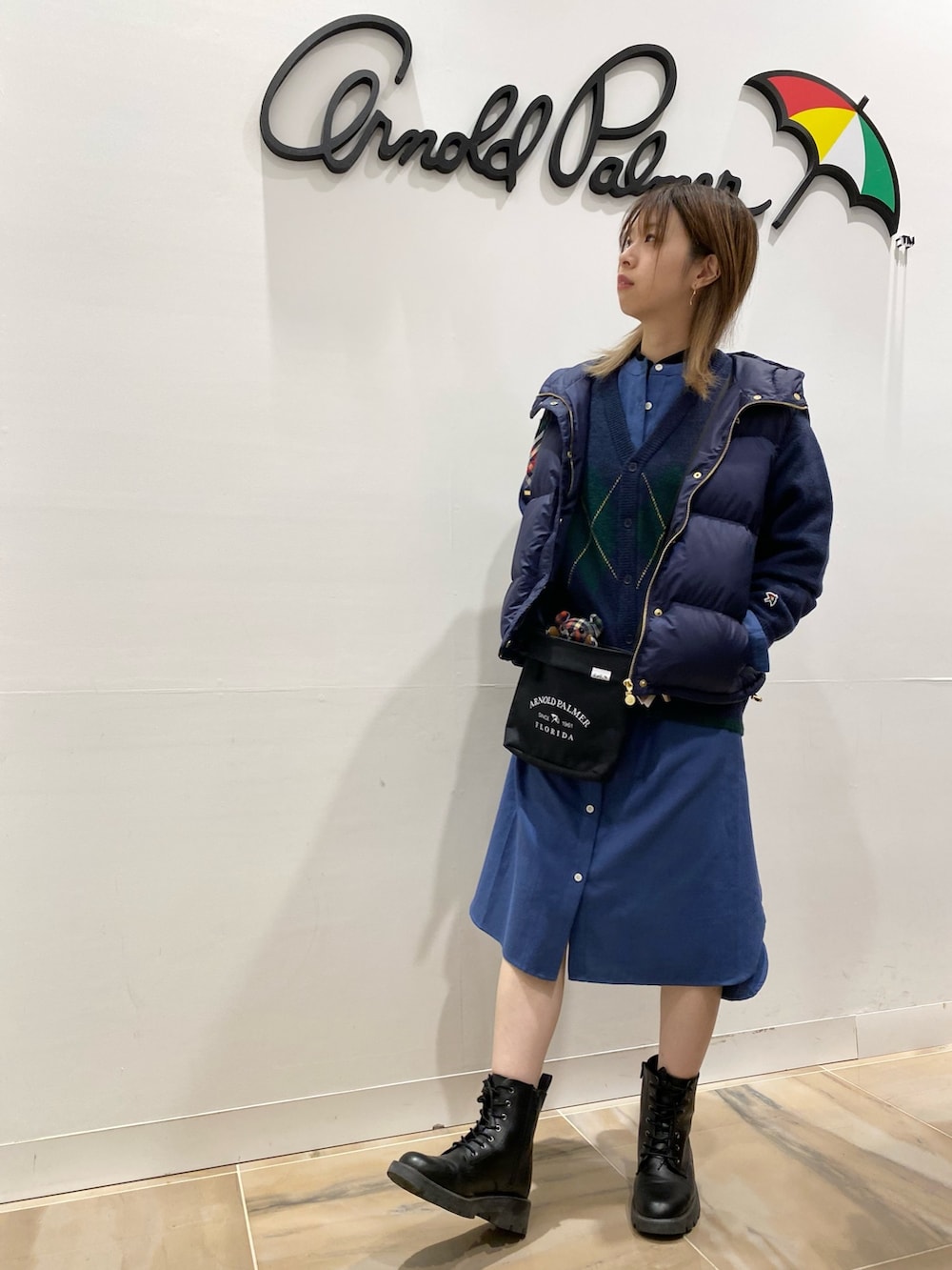 ブルー系のシャツワンピース、ブルー系のダウンベスト、ブラック系のショルダーバッグを着用したレディースの秋コーディネートの3枚目の写真