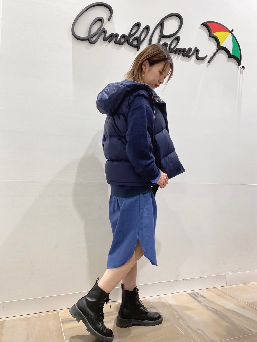 ブルー系のシャツワンピース、ブルー系のダウンベスト、ブラック系のショルダーバッグを着用したレディースの秋コーディネートの4枚目の写真