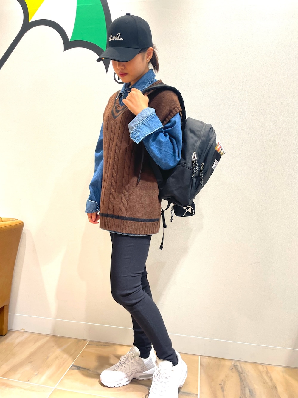 ブラウン系のニット/セーター、ブルー系のシャツ/ブラウス、ブラック系のバックパック/リュックを着用したレディースの秋コーディネートの2枚目の写真