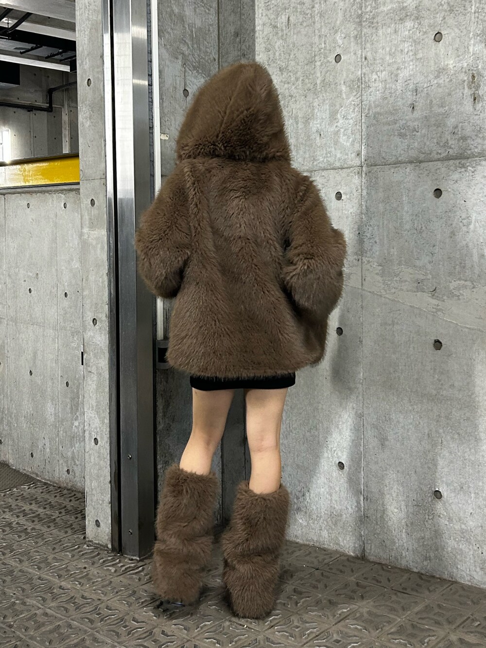 ブラウン系のブルゾン、ブラック系のブーツ、ブラウン系のレッグウォーマーを着用したレディースの秋コーディネートの2枚目の写真