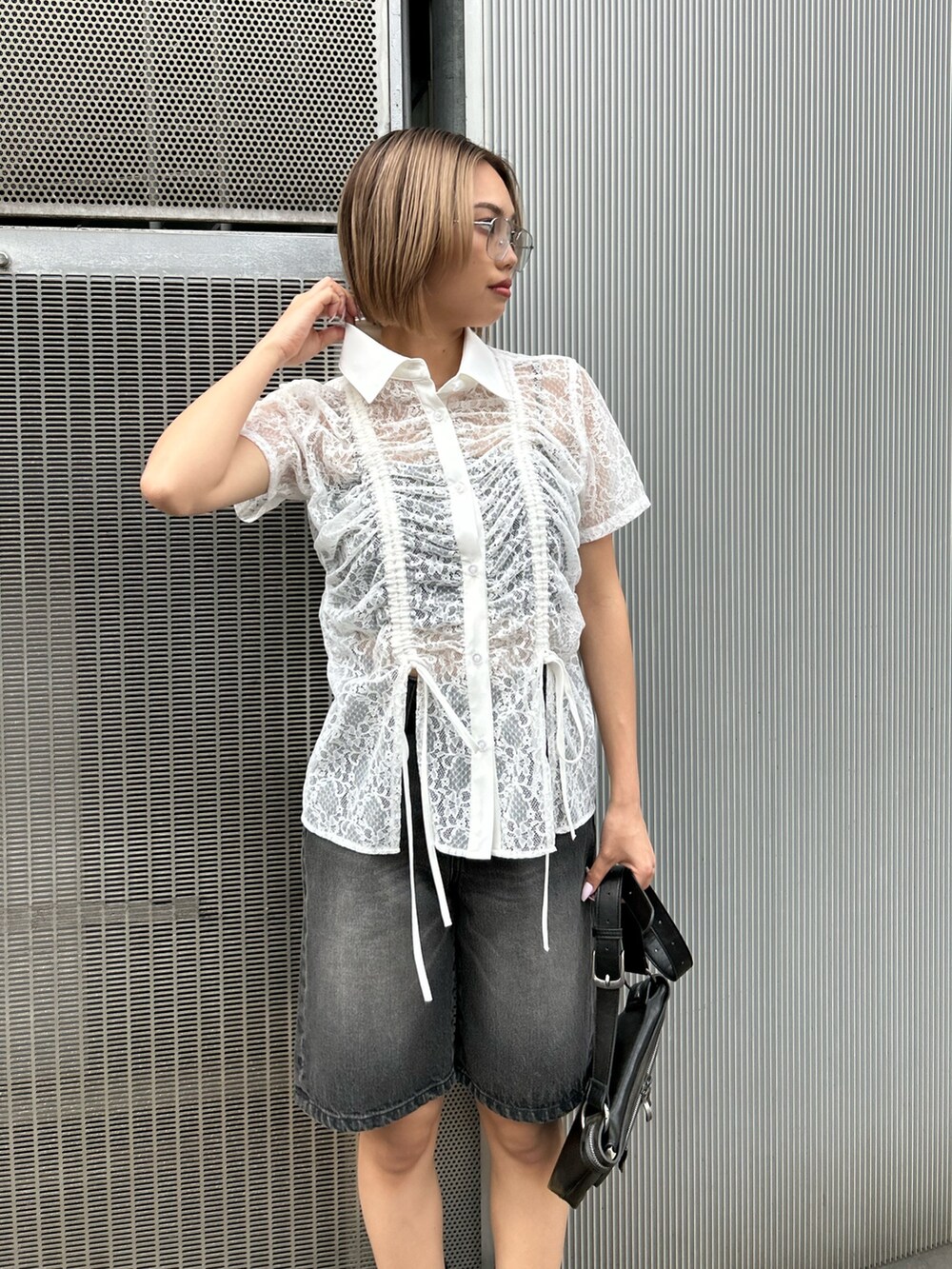 ブラック系のデニムパンツ、ホワイト系のシャツ/ブラウス、ブラック系のショルダーバッグを着用したレディースの春コーディネートの3枚目の写真