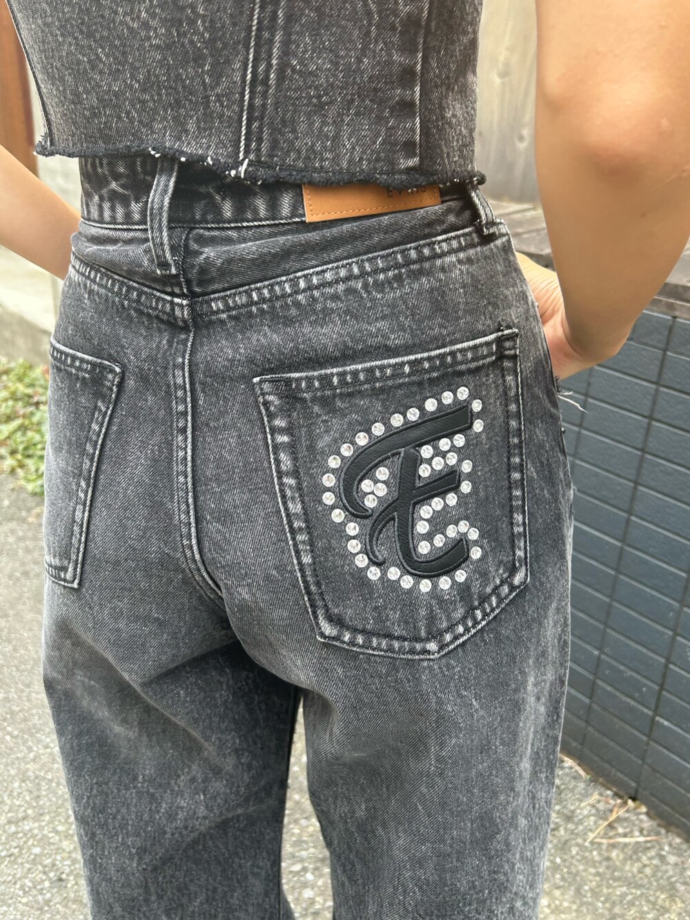 ブラック系のブーツ、ブラック系のデニムパンツ、ブラック系のキャミソールを着用したレディースの夏コーディネートの3枚目の写真