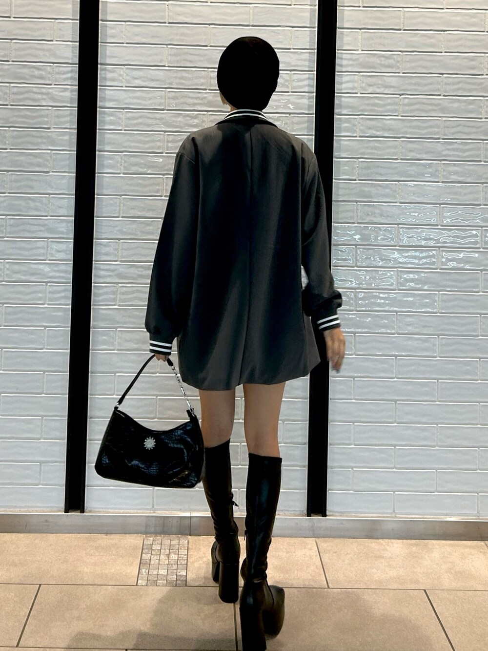 グレー系のテーラードジャケット、グレー系のスカート、ブラック系のハンドバッグを着用したレディースの秋コーディネートの3枚目の写真