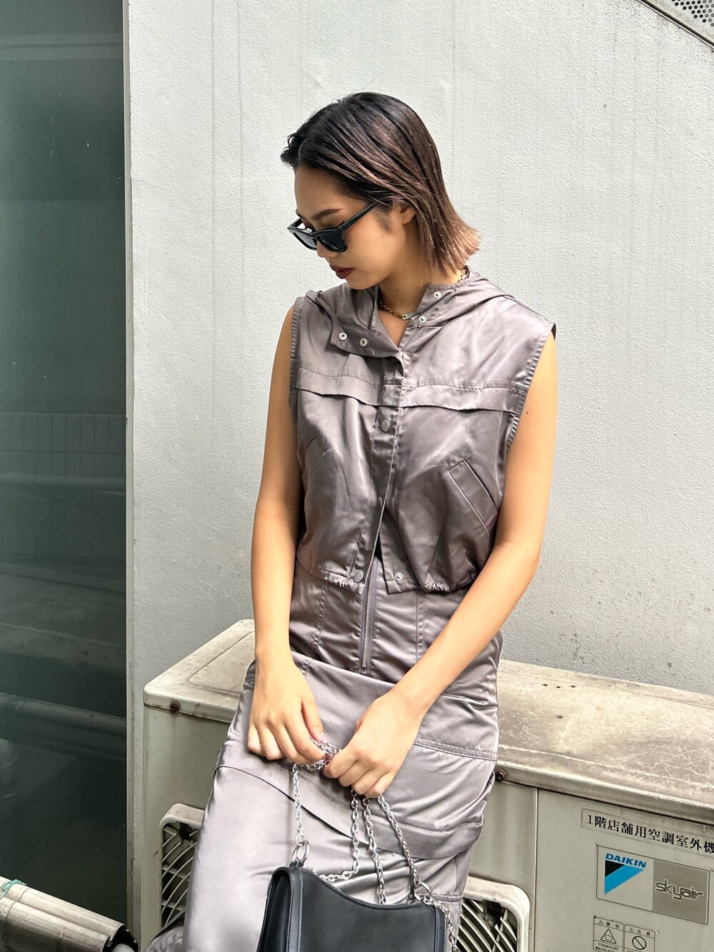 グレー系のベスト、グレー系のスカート、ブラック系のショルダーバッグを着用したレディースの夏コーディネートの3枚目の写真