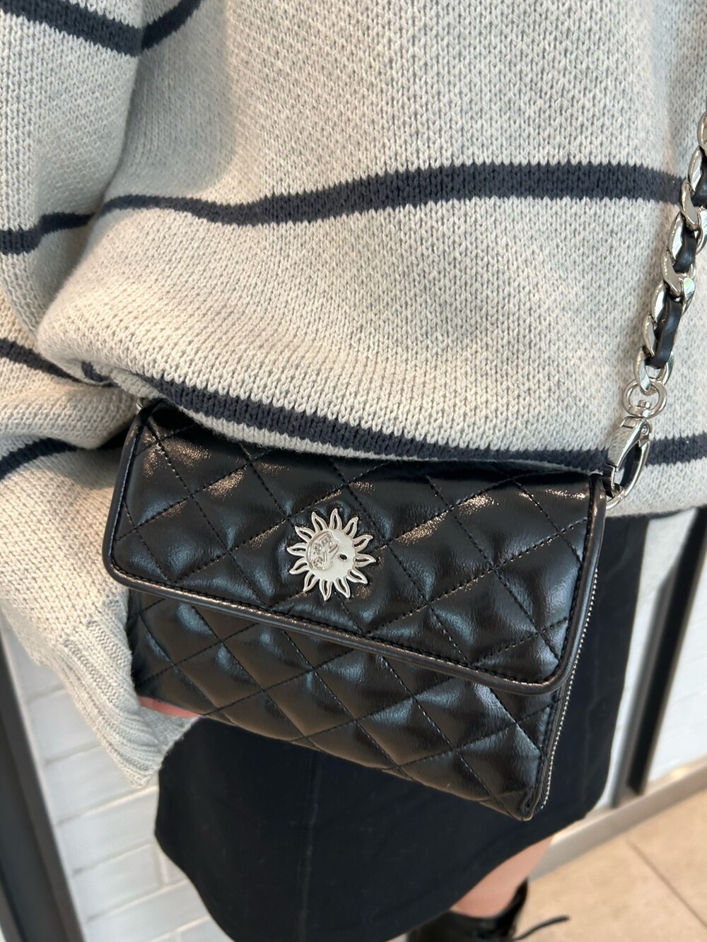 ブラック系のショルダーバッグ、ブラック系のスカート、ブラック系のブーツを着用したレディースの夏コーディネートの5枚目の写真