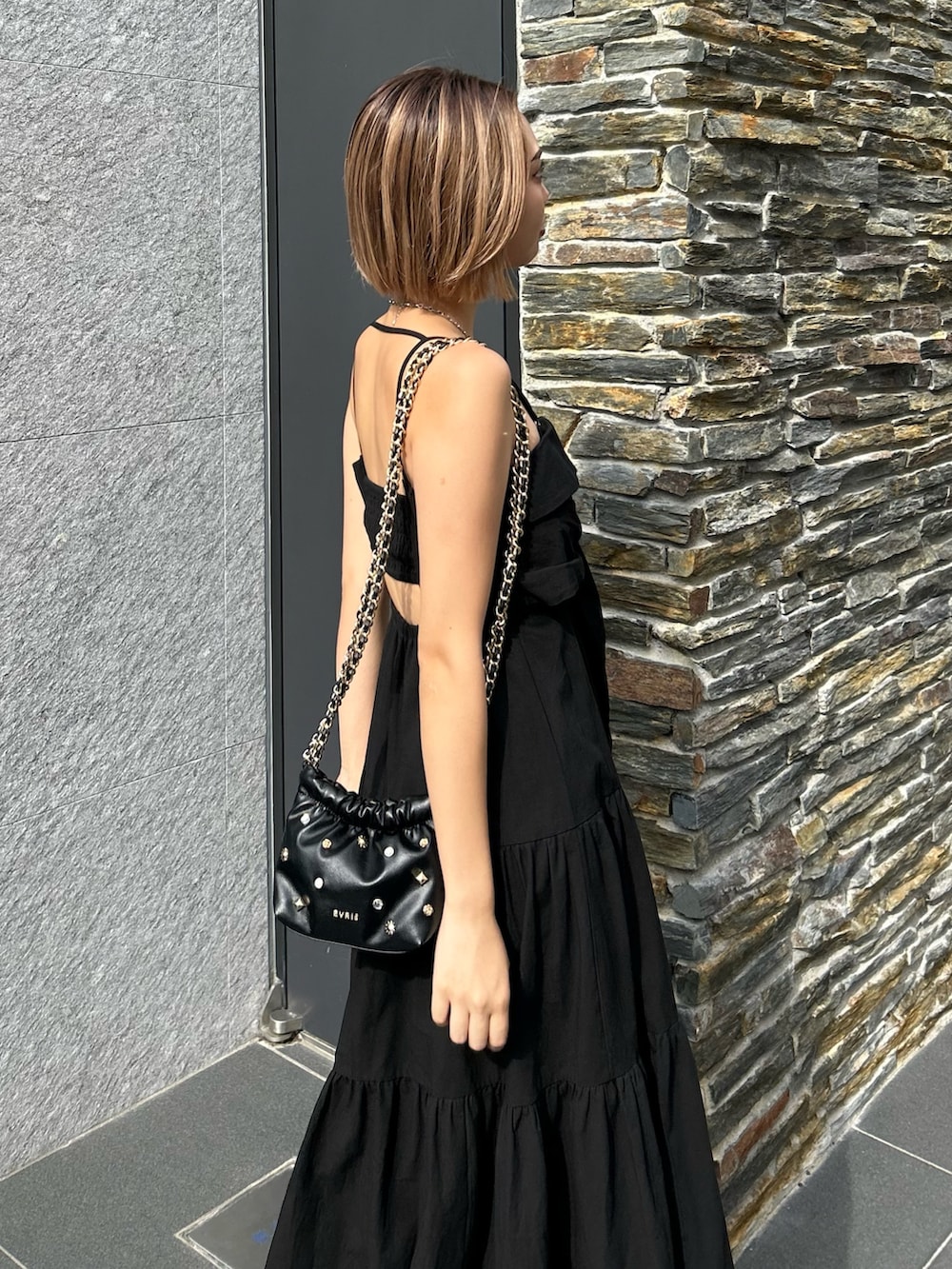 ブラック系のワンピース、ブラック系のショルダーバッグ、ブラック系のサンダルを着用したレディースの夏コーディネートの3枚目の写真