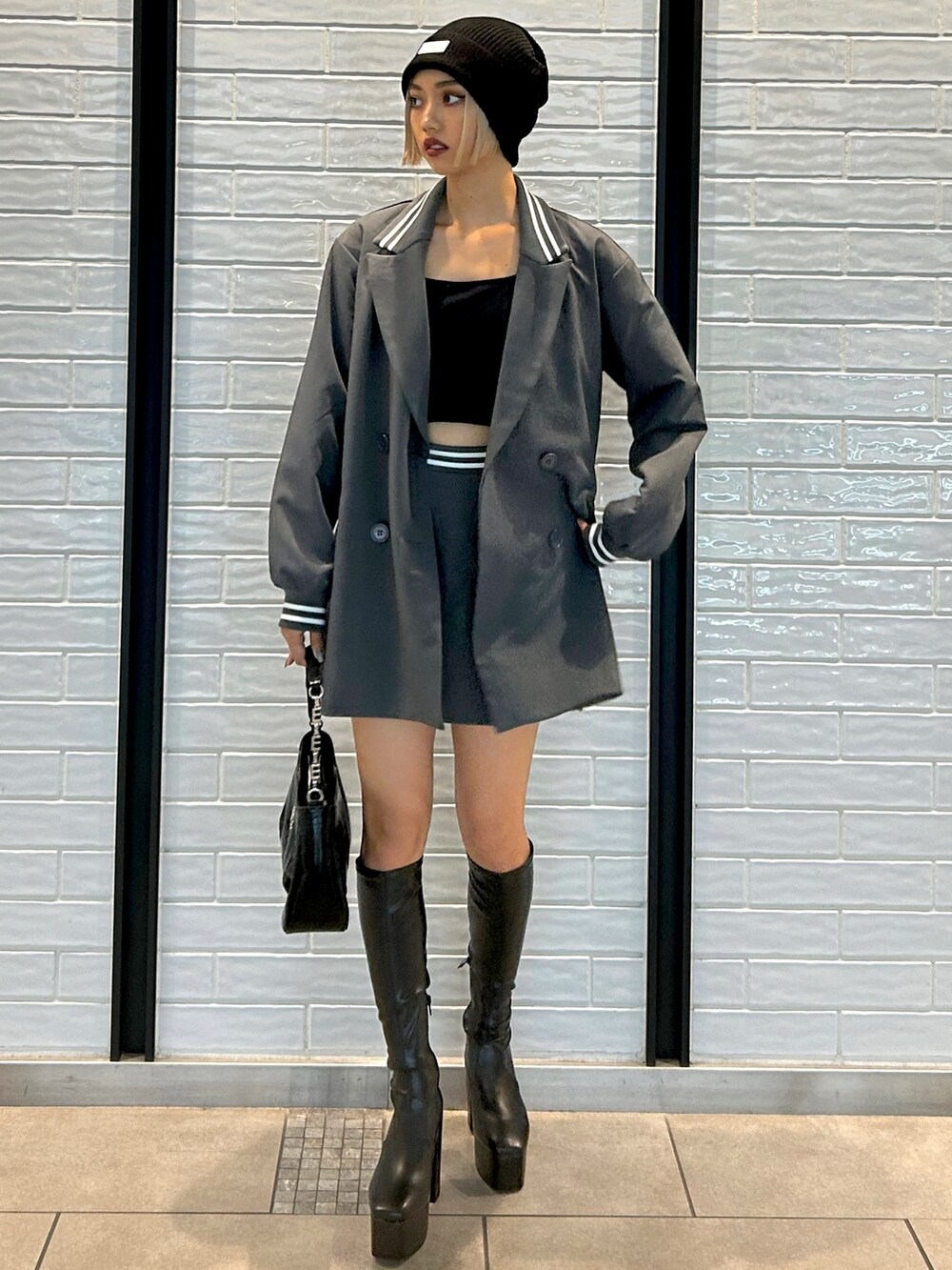 グレー系のテーラードジャケット、グレー系のスカート、ブラック系のハンドバッグを着用したレディースの秋コーディネートの2枚目の写真