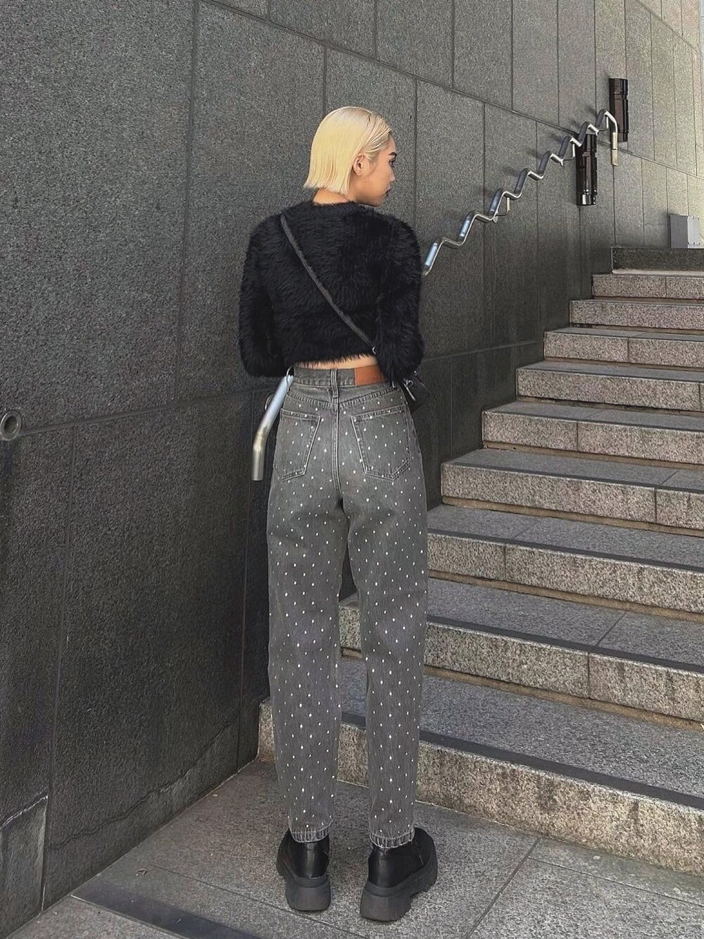 ブラック系のニット/セーター、ブラック系のデニムパンツ、ブラック系のハンドバッグを着用したレディースの秋コーディネートの2枚目の写真