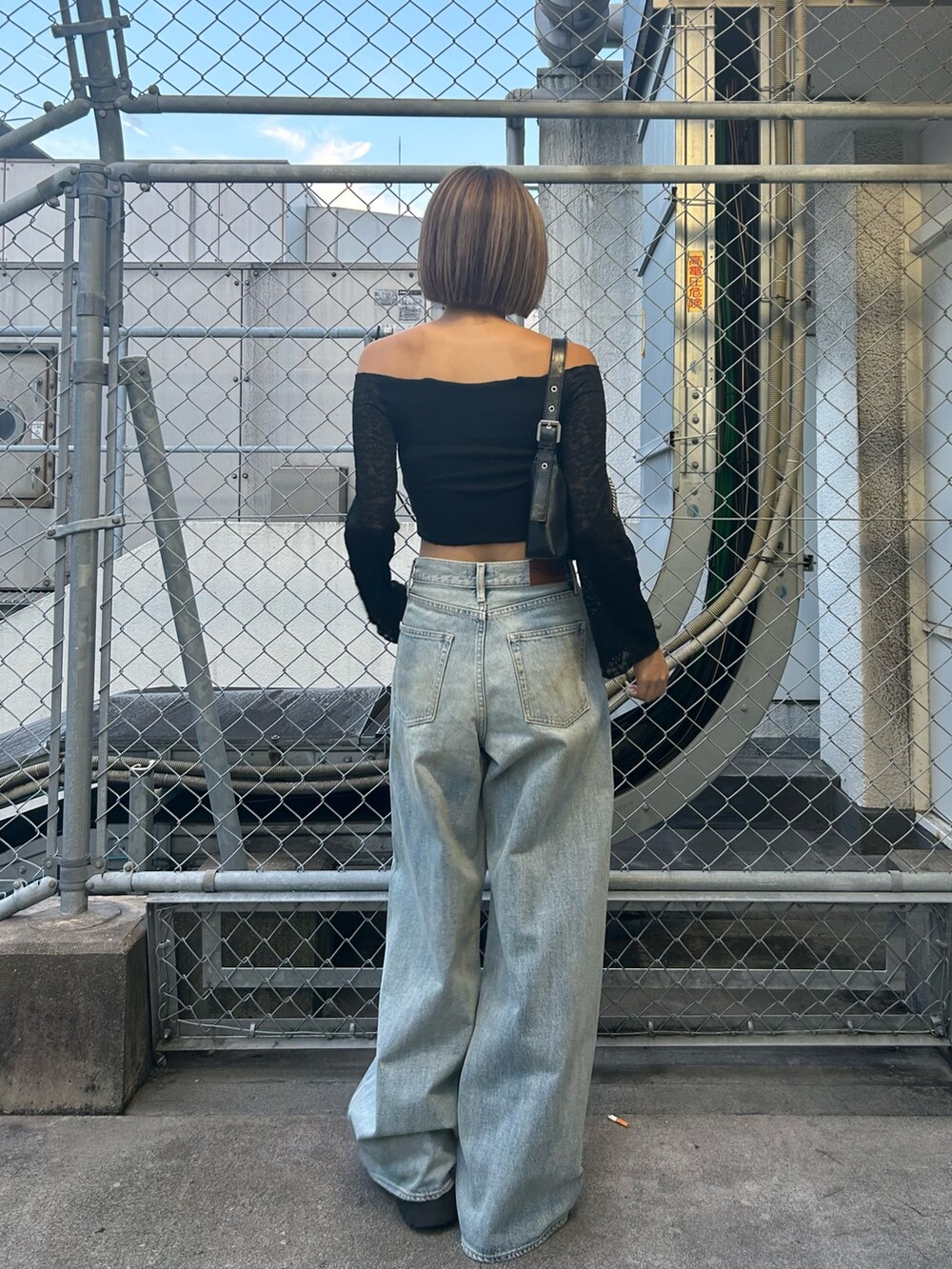 ブルー系のデニムパンツ、ブラック系のTシャツ/カットソー、ブラック系のブーツを着用したレディースの秋コーディネートの2枚目の写真