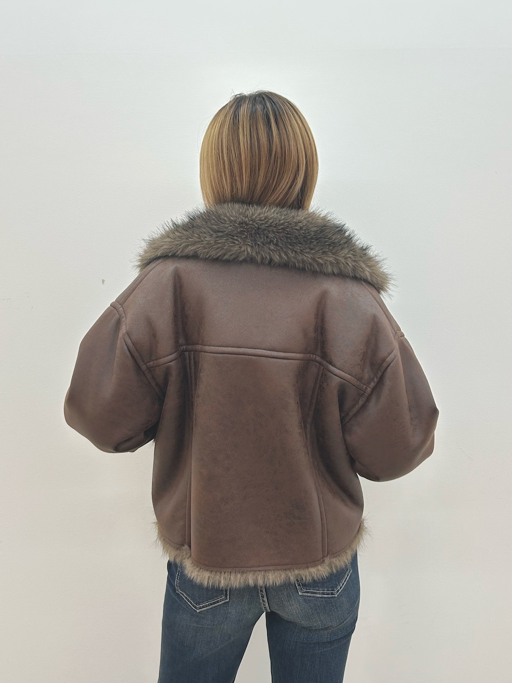 ブラウン系のブルゾン、ホワイト系のニット/セーター、ブルー系のデニムパンツを着用したレディースの秋コーディネートの6枚目の写真